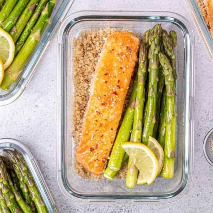 a glass food tray filed with aa slice of baked honey salmon and asparagus