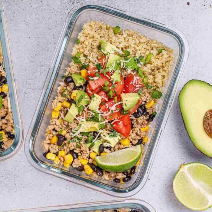 a glass food tray filled with chicken taco meal with slice of lemon and avocado on its side