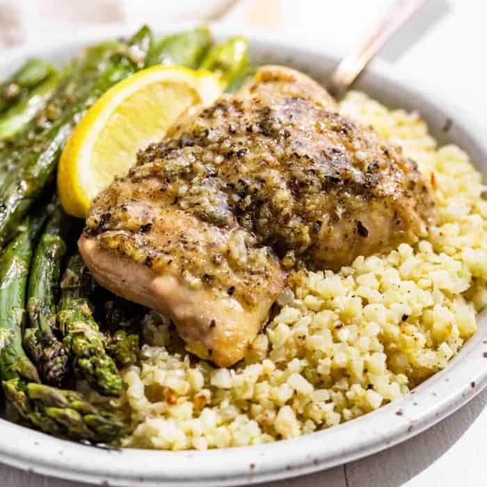 a plate filled with garlic herb chicken and asparagus with rice and slice of lemon