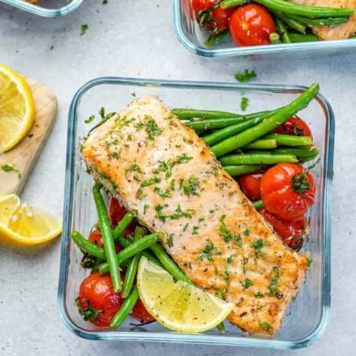 a square glass food tray filled with easy baked salmon topped with dill and tomatoes