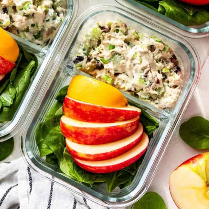 a photo of healthy tuna salad on a clear lunch box with slices of apples on the side