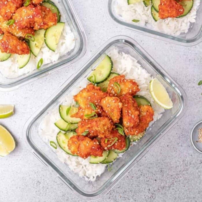 a glass tray with honey sriracha chicken meal with slices of lemon and cucumber on top