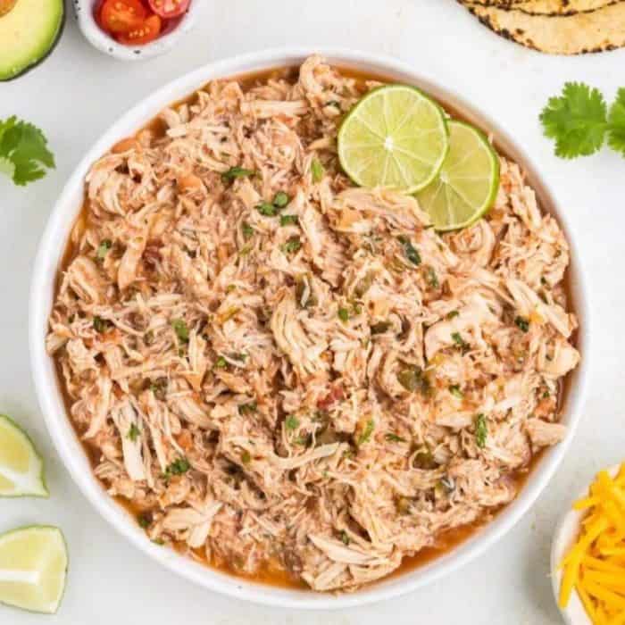 a white plate filled with salsa chicken with slices of lime on top