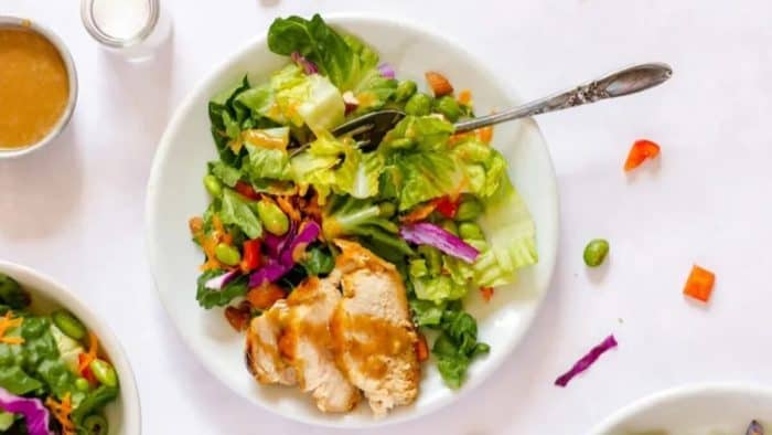 a photo of chicken thai salad placed on a white plate with a spoon