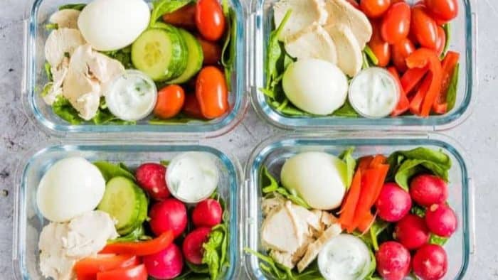 four lunchboxes filled with healthy chicken meal prep