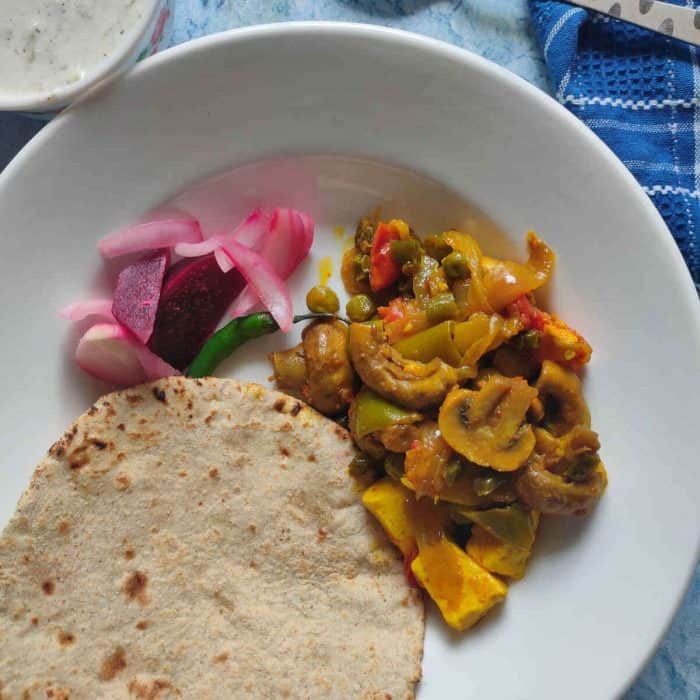 a white round plate full of mushroom stir fry and pita 