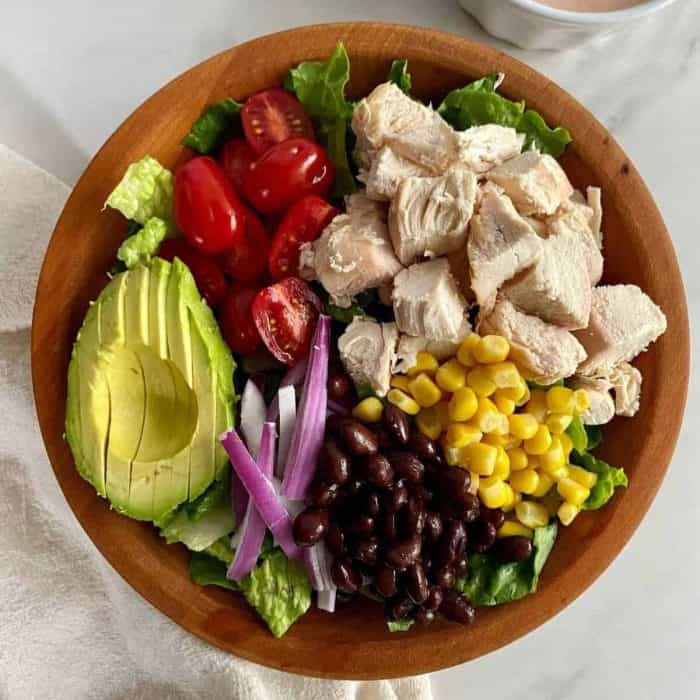 a dark wooden bowl filled with santa fe chicken salad