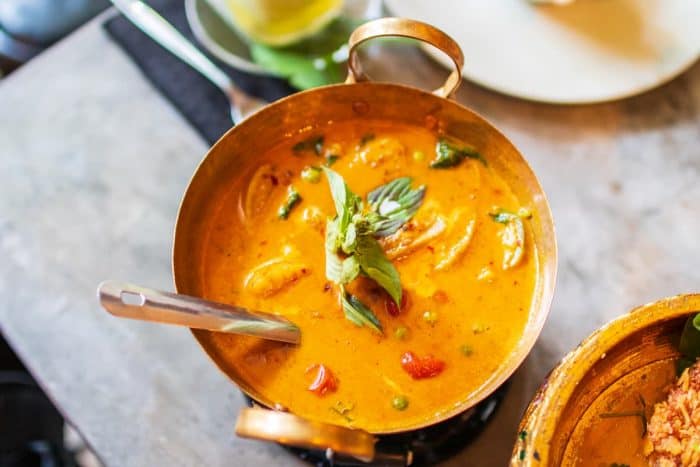A closeup of a pot of delicious Thai red curry with Duck on the table with a blurry background