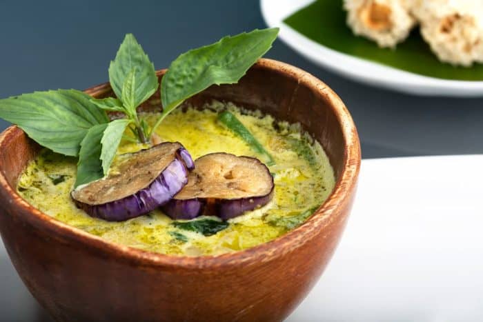 a bowl of green curry topped with egg plant