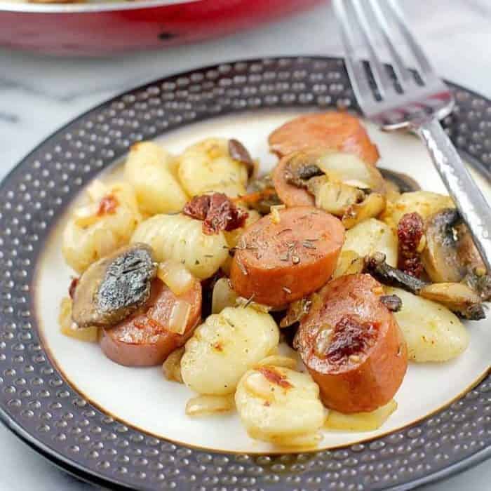 a photo of cajun sausage and gnocchi on a round plate with a fork on the side