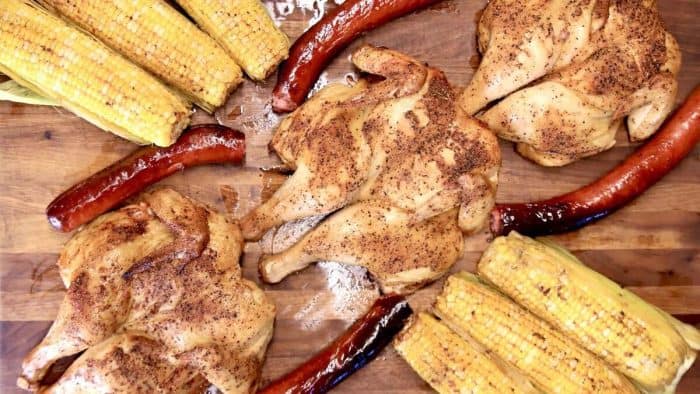 a photo of grilled chicken smoked sausage and corn on w wooden table