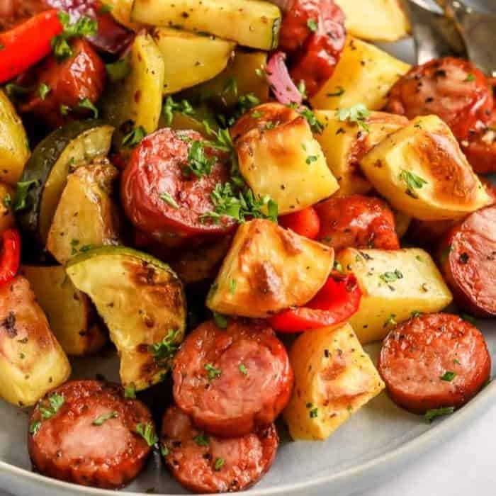 a close up photo of roasted sausage and potatoes on a plate