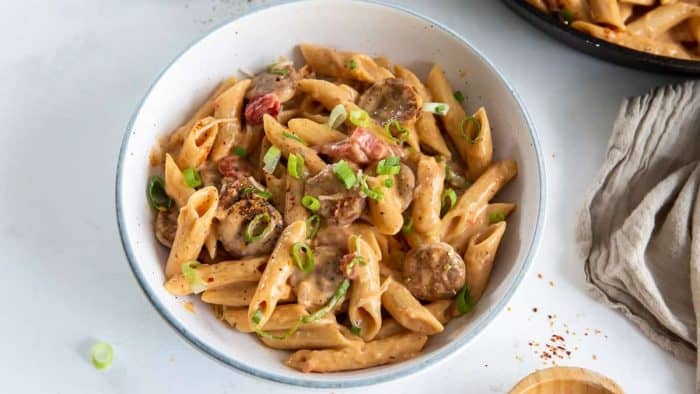 a photo of skillet sausage pasta on a white bowl placed on top of a white table