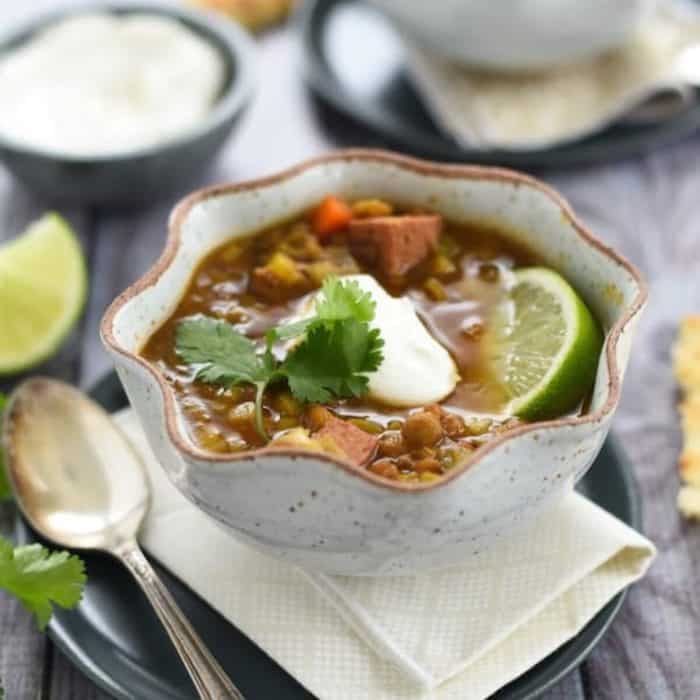 a photo of slow cooker lentil sausage soup on a bowl with spoon on the side