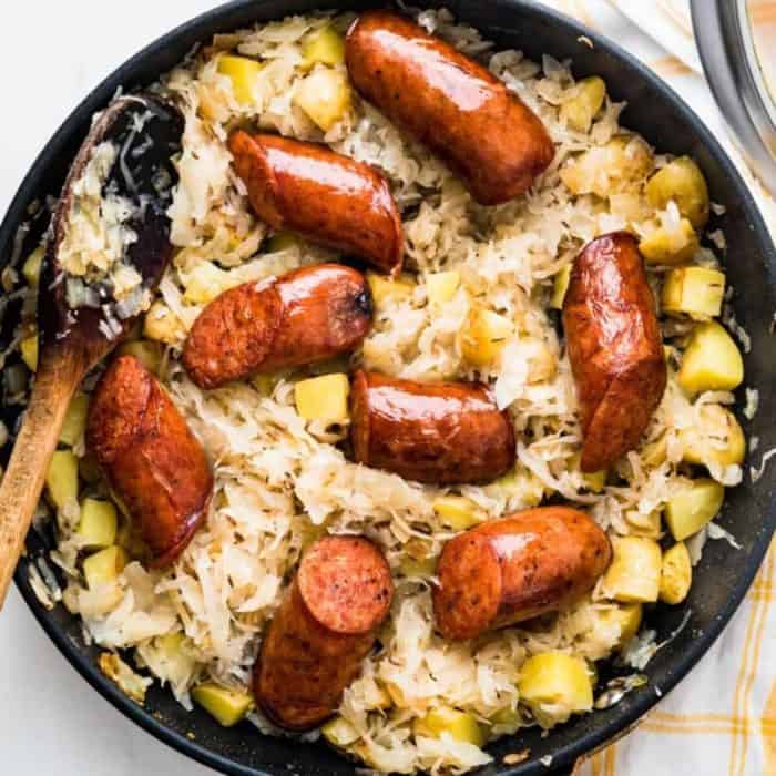 a photo of smoked sausage recipe kielbasa and sauerkraut on black pan