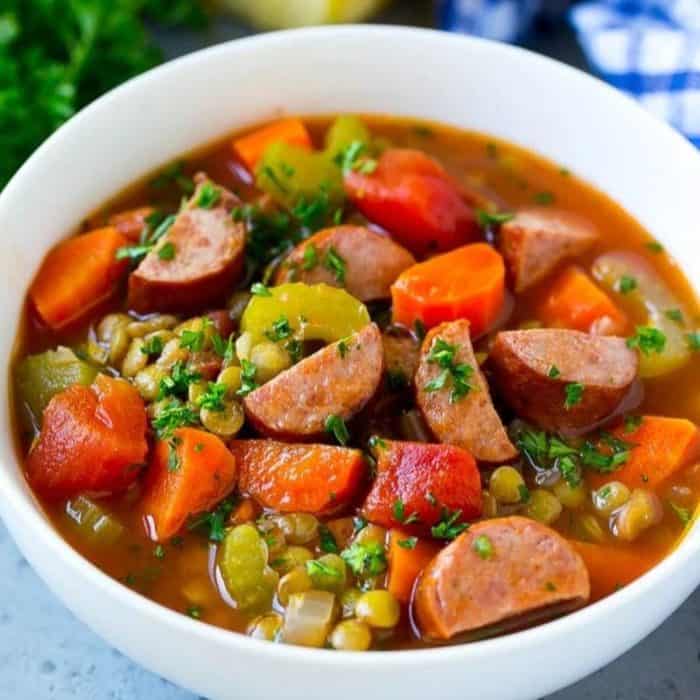 a photo of smoke sausage lentil soup on a white bowl