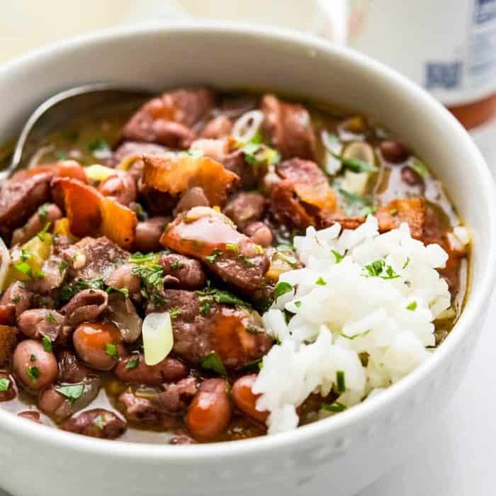 a photo of smoked sausage with red beans and rice on a white bowl