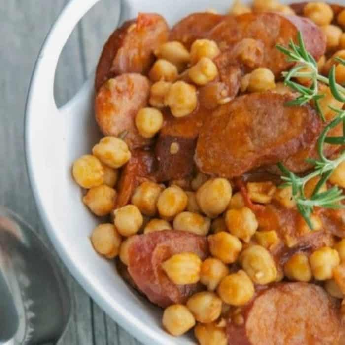 a photo of kielbasa chickpea tomato ragout on a white plate