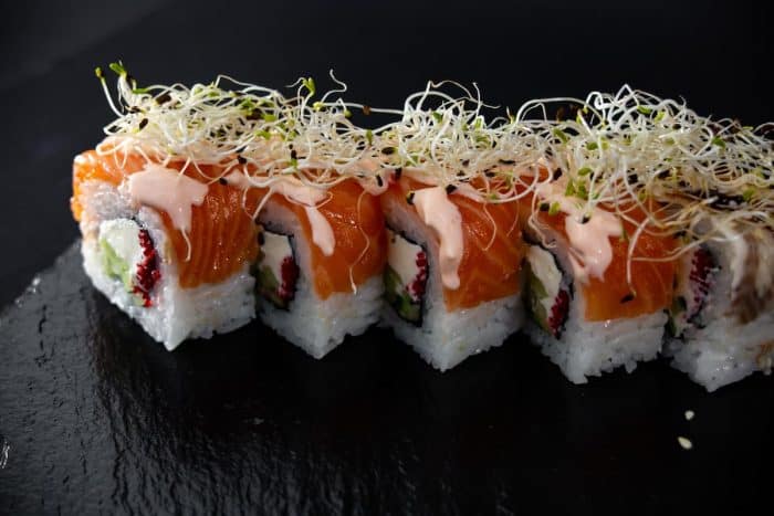 maki sushi set decorated with microgreens isolated on black background