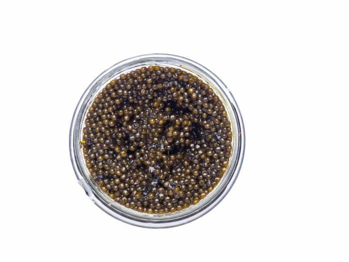 Black caviar in a little bowl on a white background.