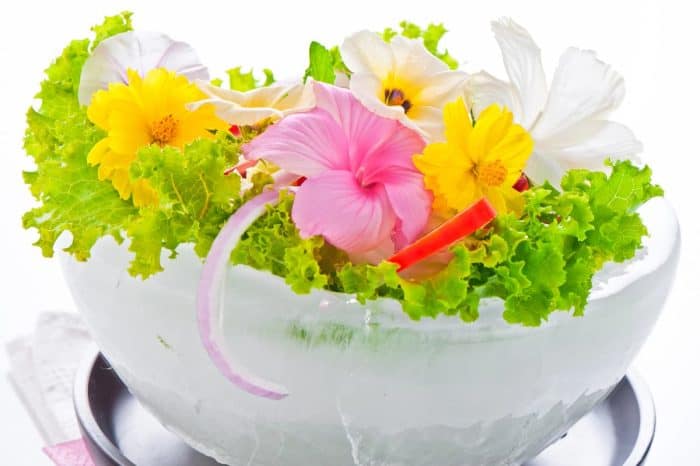 Green salad with tomatoes and various edible flowers in a bowl