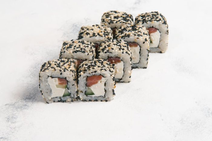 Traditional japanese rolls in black sesame seeds on light grey stone background