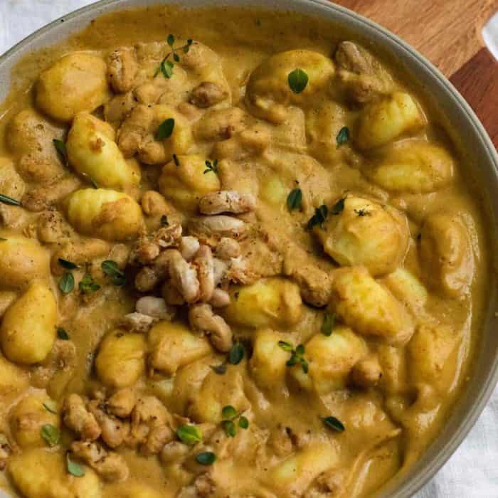a close up photo of Creamy Acorn Squash Gnocchi Pasta with Crispy White Beans on a plate