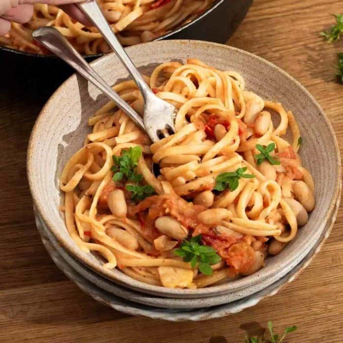 a plate of creamy Cannellini Bean and Tomato Pasta on a wooden table