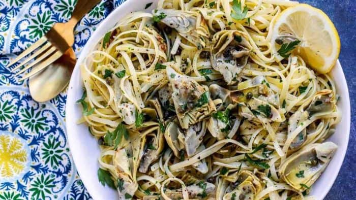 a plate filled with Vegan Lemon Artichoke Pasta and a fork on the side
