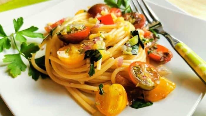 a close up photo of Vermicelli di Positano pasta on a plate with gold fork on the side