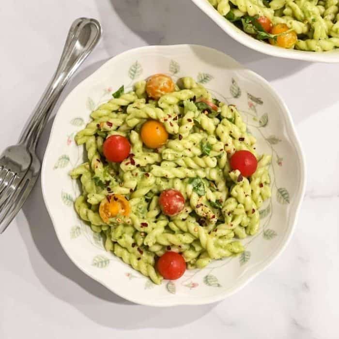 a plate of creamy Vegan Avocado Pasta with a silver fork on the side placed on a white table