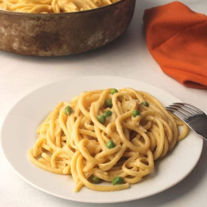a plate  of Easy Vegan Creamy Pasta with Peas with a fork on the side