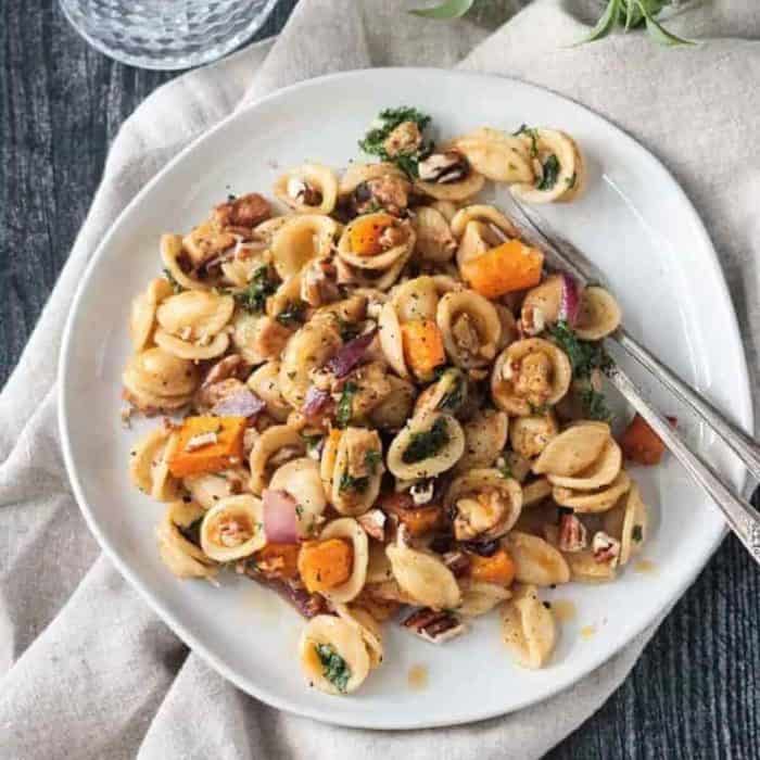 a  photo of fall Roasted Vegetable Pasta and a fork on a white plate 