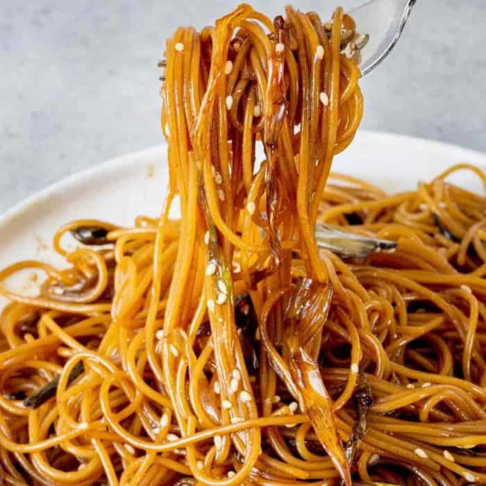 a person using a fork to get a roll of Scallion Oil Noodles