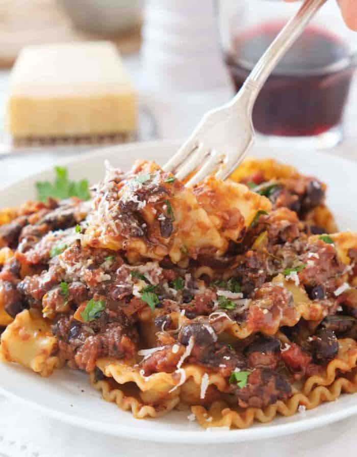 a close up photo of vegan Pasta With Black Beans with silver fork on the top