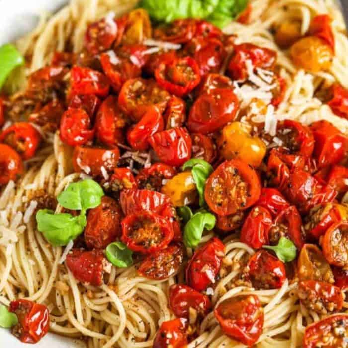 a close up photo of Roasted Cherry Tomato Pasta topped with lots of sliced cherry tomatoes