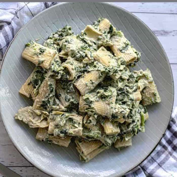a plate off creamy Vegan Pasta with Spinach and Artichokes on a table
