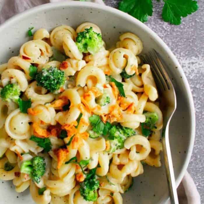 a plate filled with Creamy Tahini Pasta with Garlic and Broccoli and a fork on the side