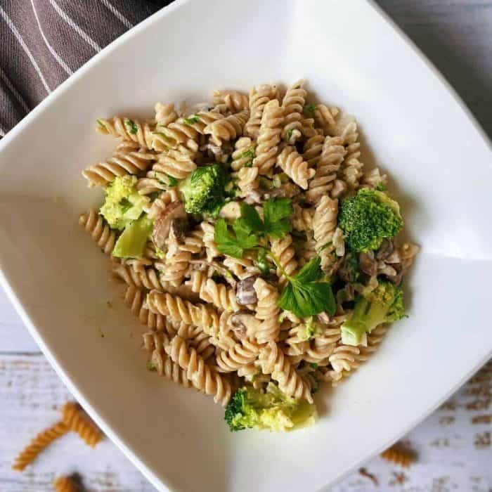 a  photo of creamy Vegan Mushroom and Broccoli Pasta on a square white plate