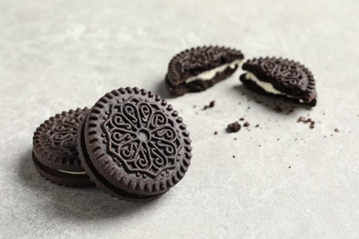 Tasty chocolate cookies with cream on grey background