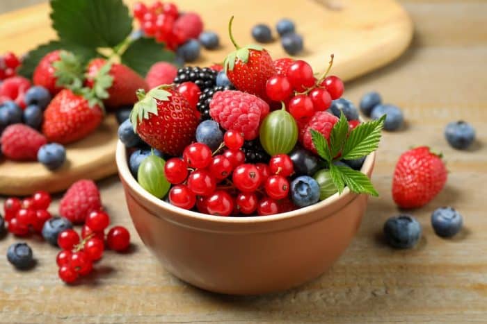 Remove BG Save Share Sample Mix of different fresh berries in bowl on wooden table
