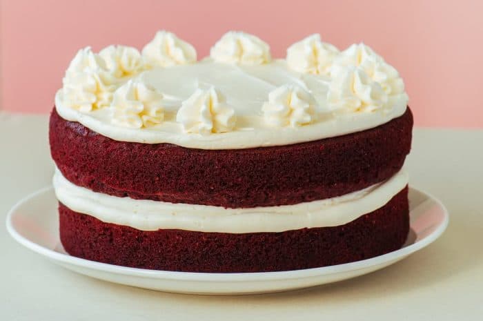 Red velvet cake with cream cheese frosting on a white plate