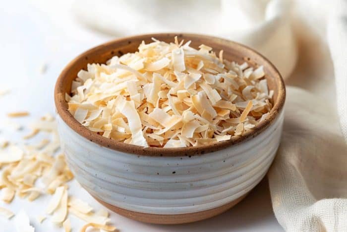realistic image of a bowl of toasted coconut flakes