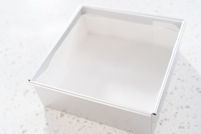 Line an eight-inch square pan with parchment paper, leaving enough overhang on the sides to help you lift out the fudge once it's set.