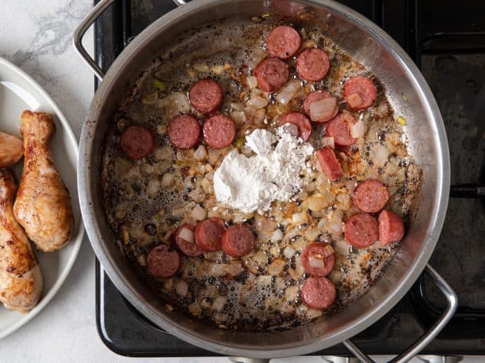 Add shallot and garlic to the same pan and cook for 3 to 4 minutes or until shallots soften. Add sausages and cook until brown. Sprinkle flour in the pan.