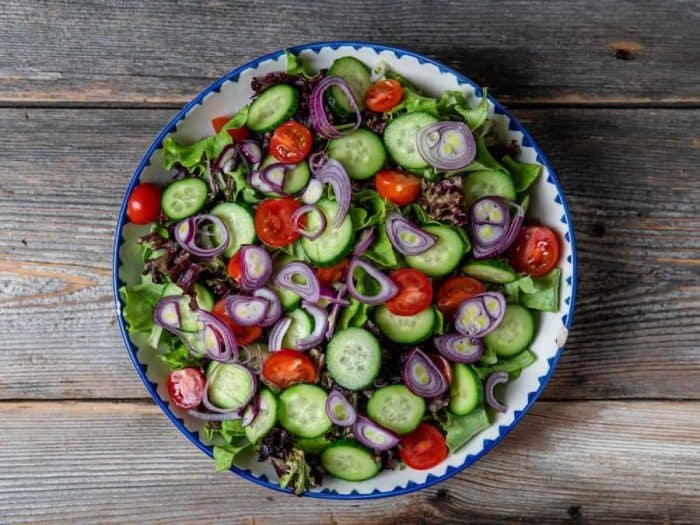 Divide salad greens between 4 plates or bowls. Top with shallots, tomatoes, and cucumbers.