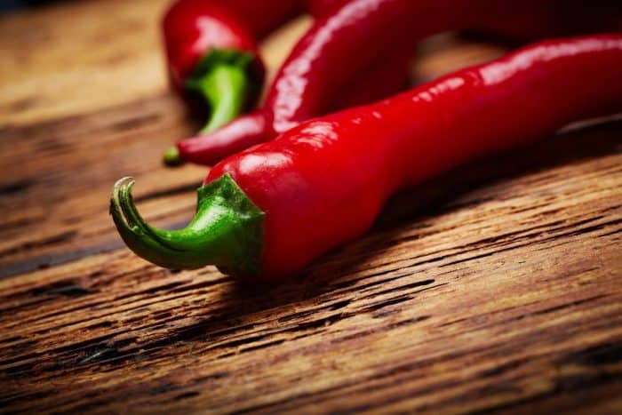 a close up image of a red chili pepper placed on a wooden chopping board