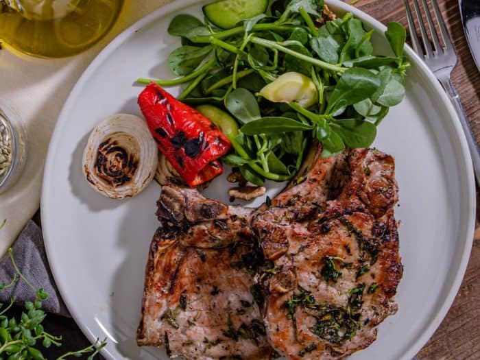 These grilled pork chops are not your average dinner; they're a symphony of basil, thyme, and rosemary, married with the unmistakable char of a grill. 