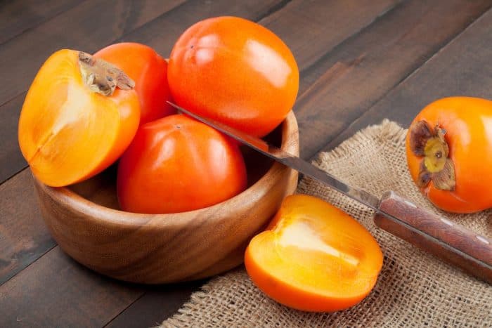 fresh persimmons placed on a wooden table