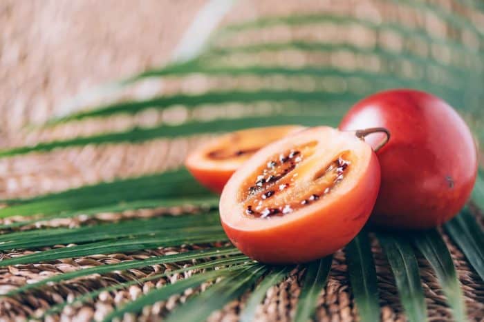 Tamarillo fruit or terong belanda with palm leaves on rattan background
